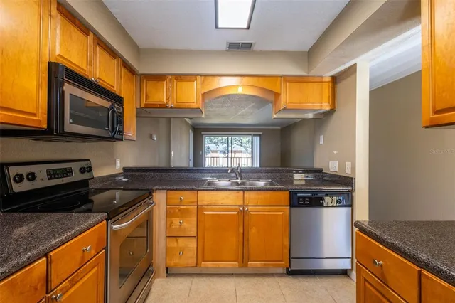 a kitchen with stainless steel appliances granite countertop a stove a sink and a microwave