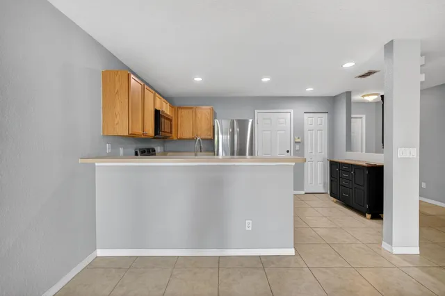 a view of kitchen with stainless steel appliances granite countertop a refrigerator a stove a sink and a microwave
