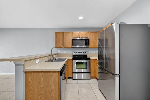 a kitchen with stainless steel appliances granite countertop a refrigerator sink and stove
