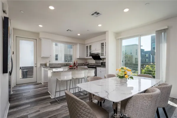 a kitchen with a dining table chairs and refrigerator