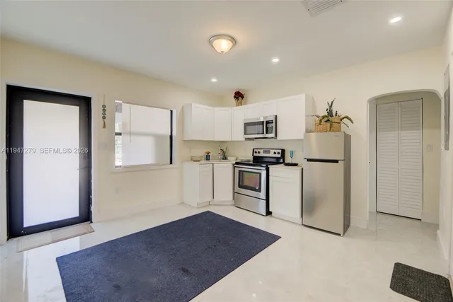 a kitchen with white cabinets and refrigerator
