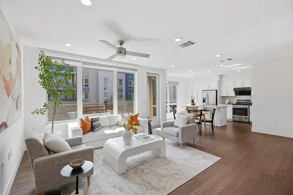 a living room with furniture kitchen view and a large window