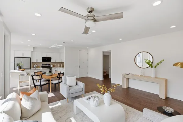 a living room with furniture kitchen view and a chandelier