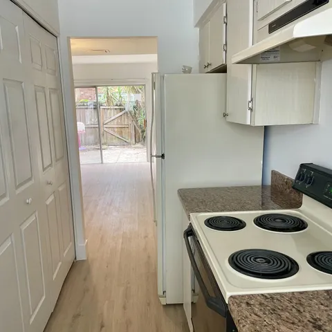 a kitchen with white cabinets and wooden floor