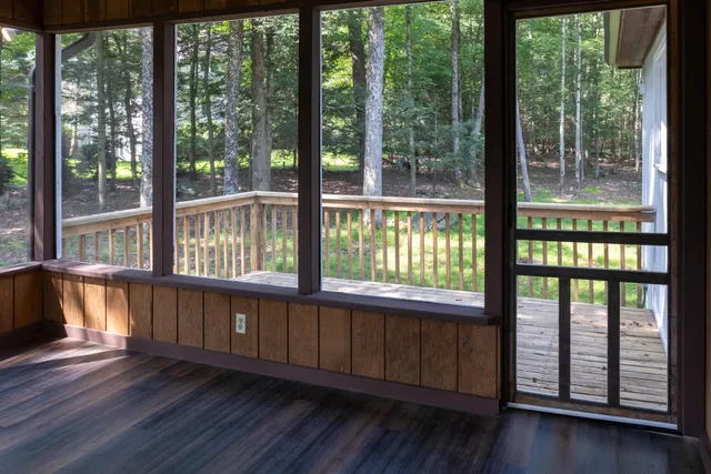 a view of an empty room with wooden floor and floor to ceiling windows
