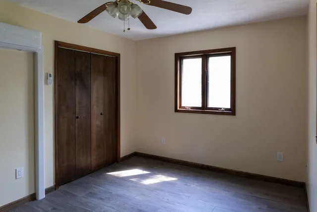an empty room with wooden floor closet and windows