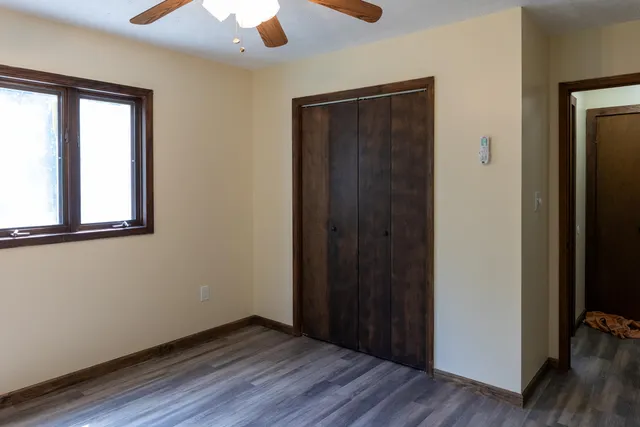 an empty room with wooden floor closet and windows