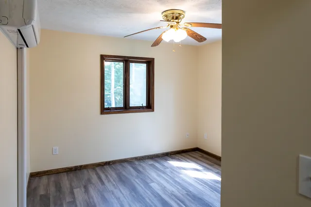 a view of an empty room with a window and wooden floor