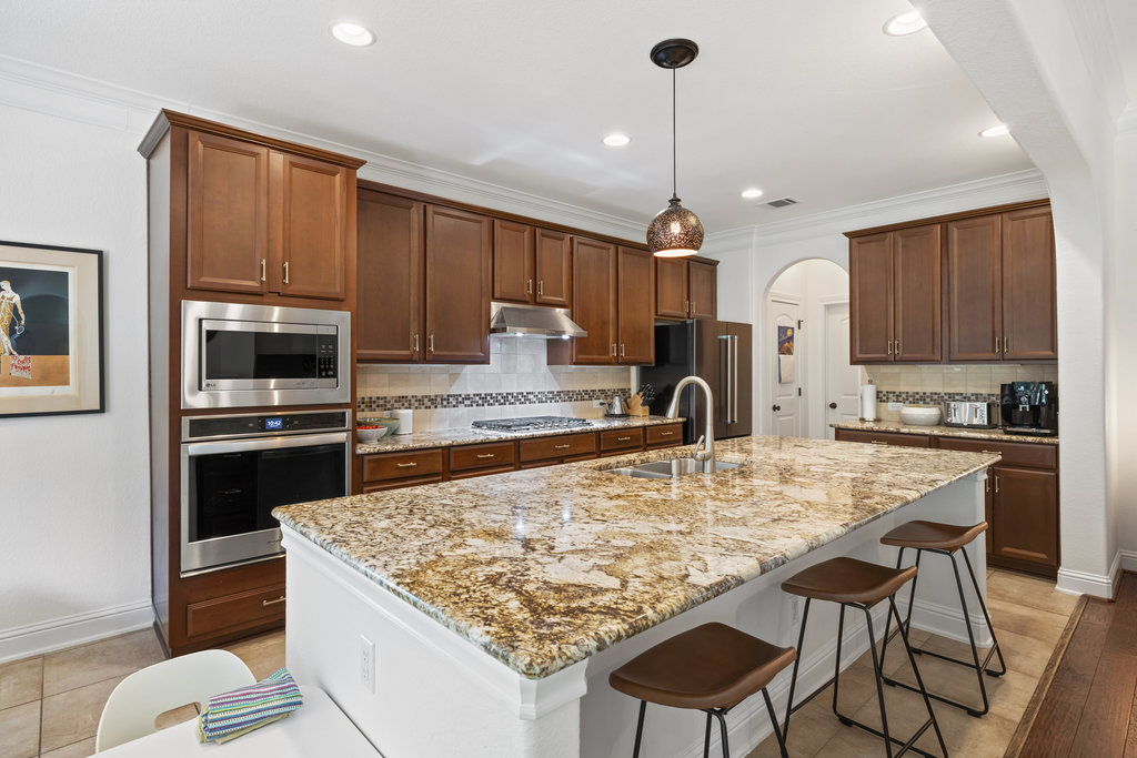 9116 Villa Norte Drive Austin, TX 78726 - Photo 11 of 40 a kitchen with granite countertop a stove refrigerator and microwave