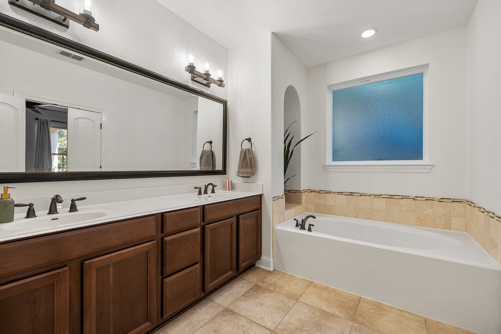 9116 Villa Norte Drive Austin, TX 78726 - Photo 17 of 40 a bathroom with a bathtub a double vanity sink and mirror