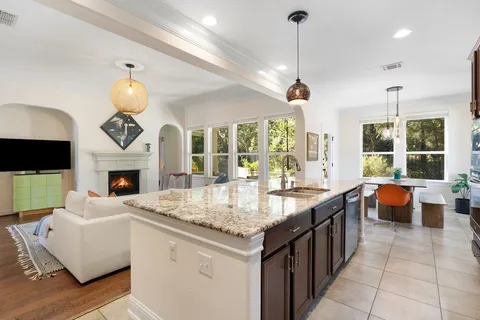 a kitchen with stainless steel appliances granite countertop a sink a stove and a wooden cabinets