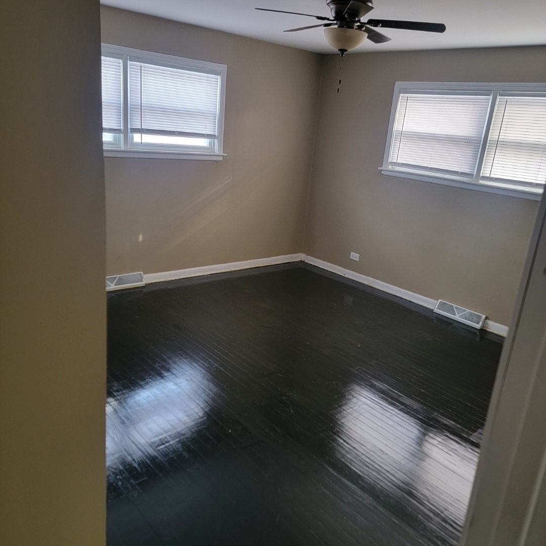 16444 Wolcott Avenue Markham, IL 60428 - Photo 12 of 18 a view of an empty room with wooden floor and a window