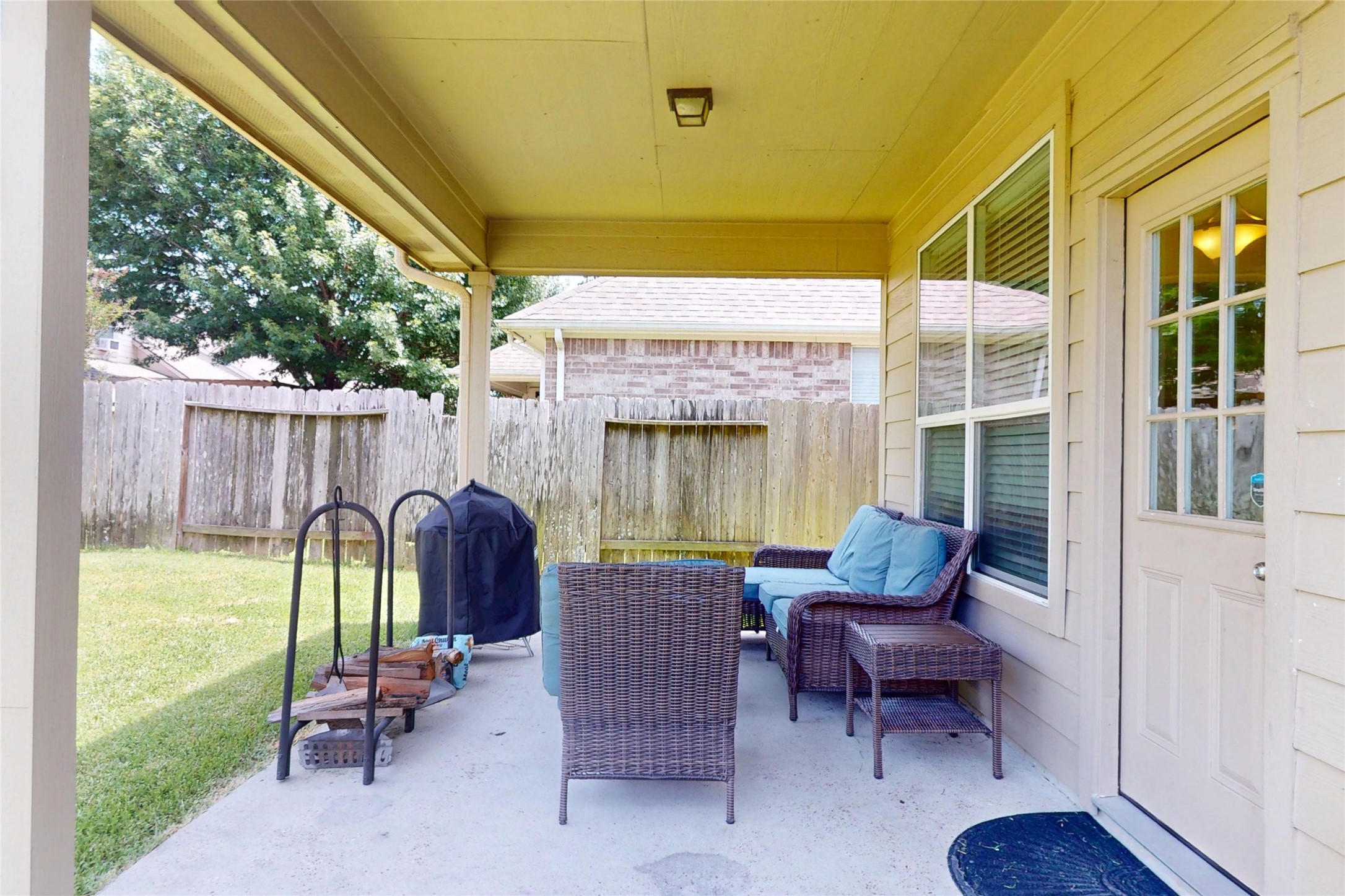 17402 Rainer Valley Lane Humble, TX 77346 - Photo 28 of 33 This photo showcases a cozy covered patio with comfortable outdoor seating, perfect for relaxing or entertaining. Plenty of room for a small grill area, and is enclosed by a wooden fence for privacy, overlooking a grassy yard.