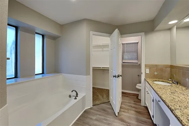 a bathroom with a granite countertop sink and a bathtub