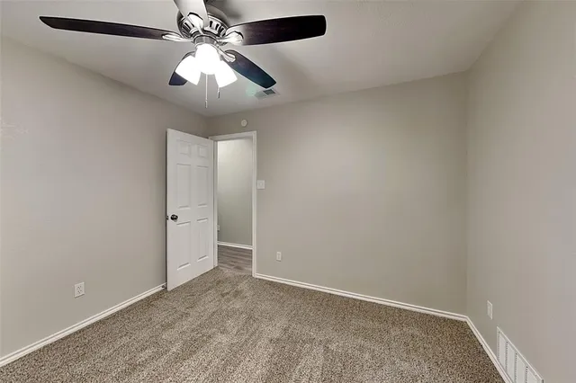 an empty room with closet and a chandelier fan