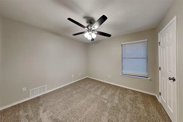 a view of an empty room and window and ceiling fan
