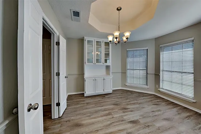 an empty room with wooden floor cabinet and windows