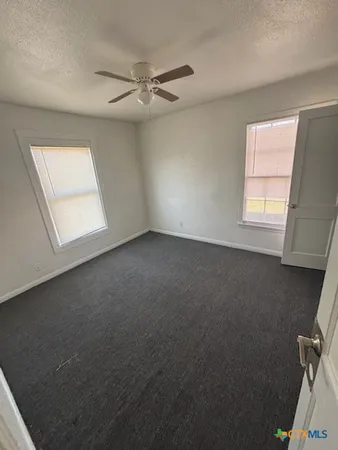 an empty room with windows and fan