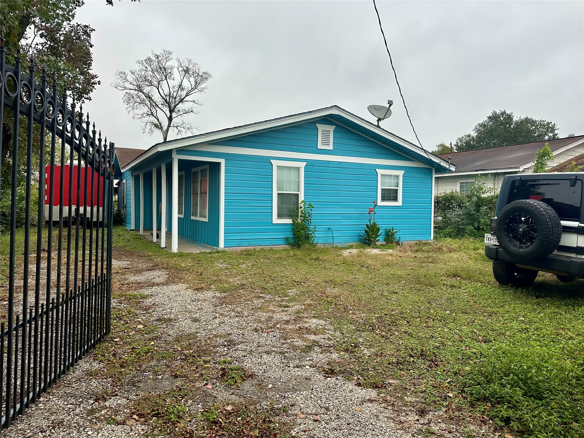 a view of a house that has a small yard and large trees