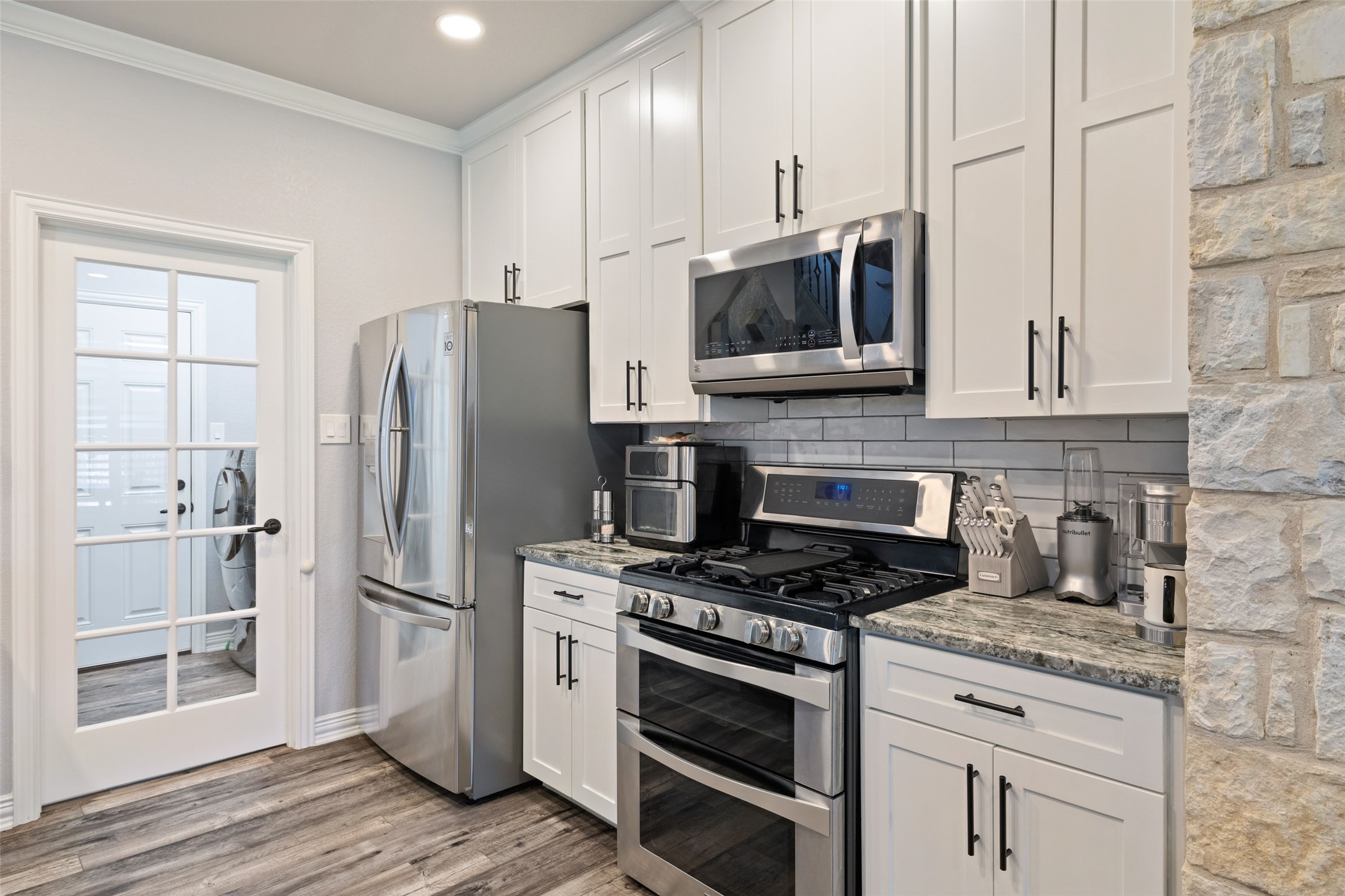 134 Prairie Springs Cove Georgetown, TX 78626 - Photo 12 of 34 a kitchen with stainless steel appliances white cabinets a stove a microwave and a refrigerator