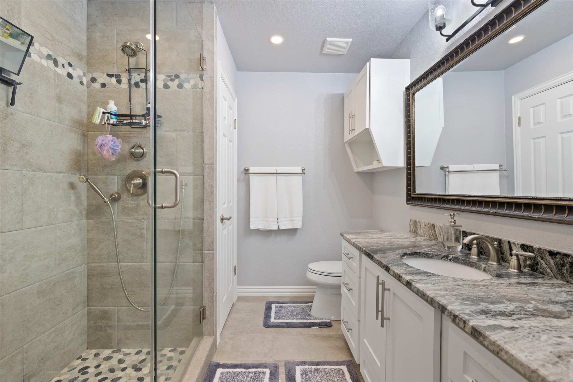 134 Prairie Springs Cove Georgetown, TX 78626 - Photo 21 of 34 a bathroom with a granite countertop sink a toilet a shower and a mirror