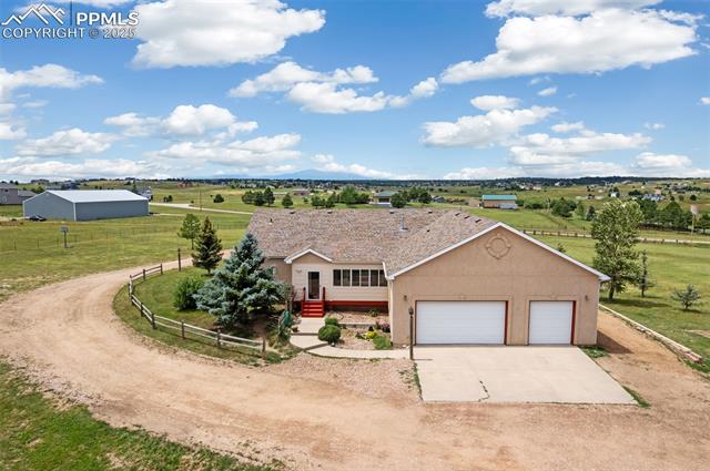 13775 Woodlake Road Elbert, CO 80106 - Photo 44 of 44 View of front of house with driveway, a rural view, stucco siding, and a garage