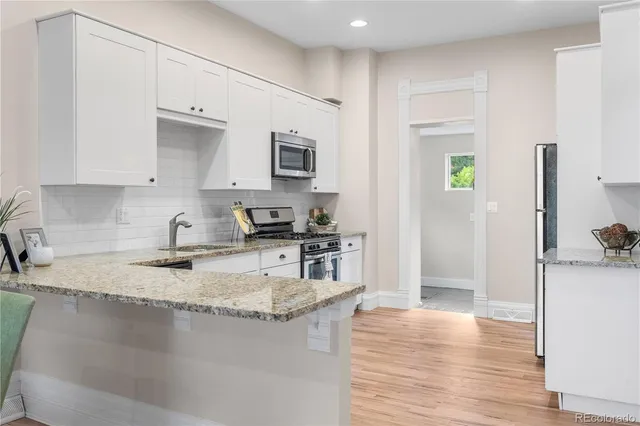 a kitchen with kitchen island granite countertop a stove top oven a sink a counter space and cabinets
