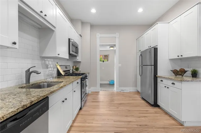a kitchen with granite countertop a sink stove and refrigerator