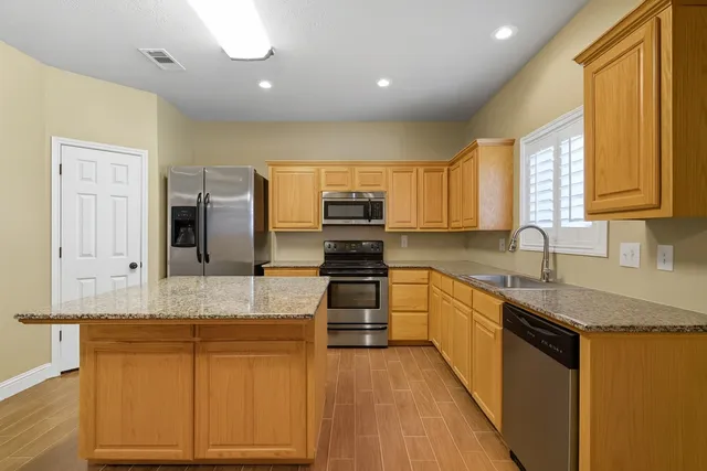 a kitchen with granite countertop a sink stove cabinets and refrigerator