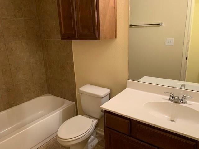 714 Parkplace Ridge Princeton, TX 75407 - Photo 8 of 15 Bathroom featuring a white bathtub, ceramic tile shower surround, wood-finish vanity with an integrated sink, and wall-mounted storage cabinetry