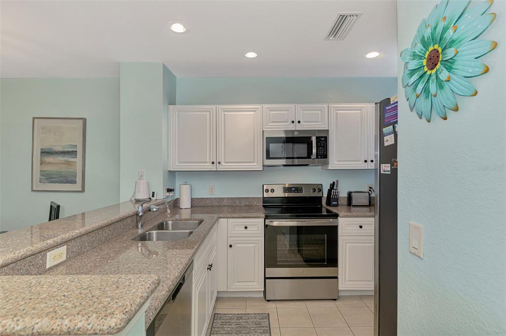 8409 Placida Road, Unit 206 Placida, FL 33946 - Photo 21 of 67 a kitchen with kitchen island granite countertop a sink a stove and microwave
