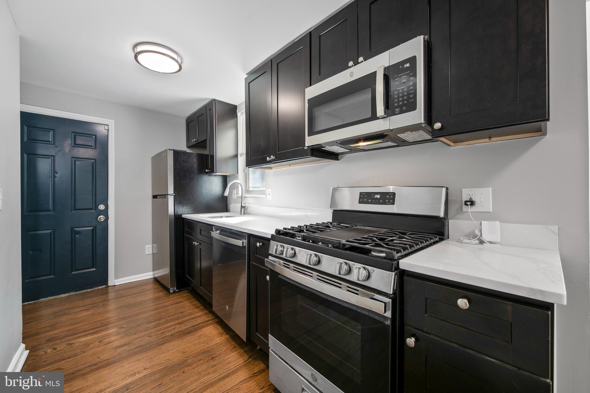 1226 America Road Camden, NJ 08104 - Photo 12 of 30 a kitchen with stainless steel appliances granite countertop a stove microwave and refrigerator