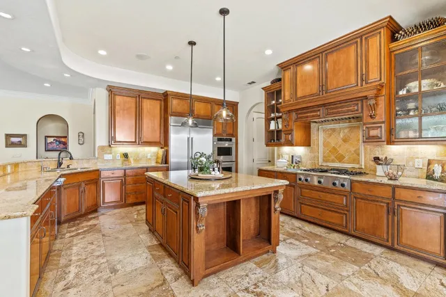 a kitchen with stainless steel appliances granite countertop a stove a sink dishwasher and a flat screen tv