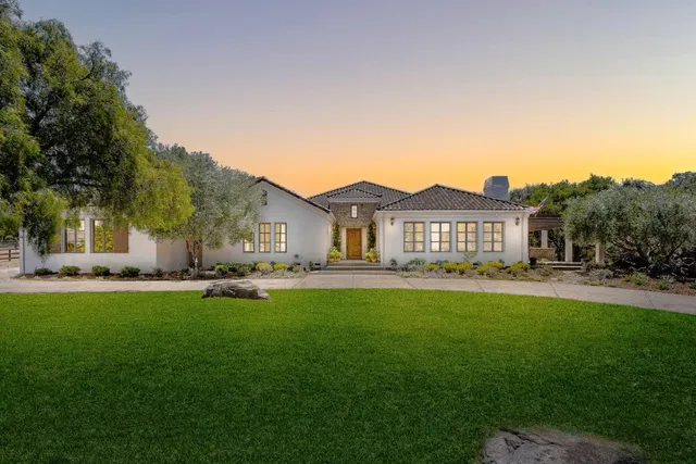 a view of a house with a big yard plants and large trees