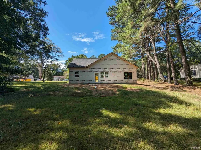 a view of a white house that has a big yard with wooden fence