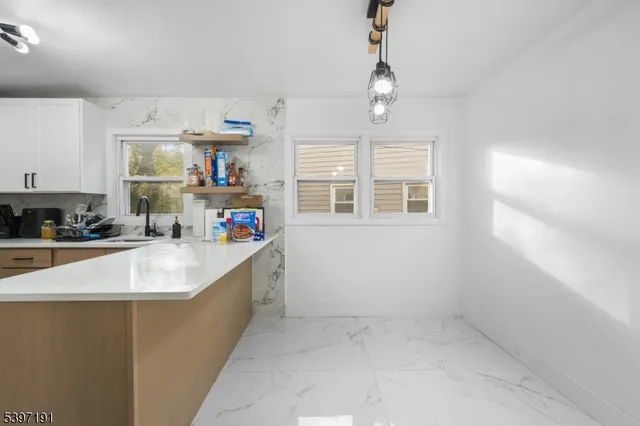 a large kitchen with kitchen island a large counter space a sink a window and stainless steel appliances