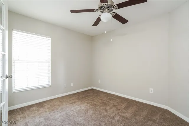 an empty room with a window and a fan