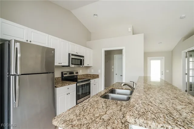 a kitchen with stainless steel appliances granite countertop a refrigerator stove top oven and sink