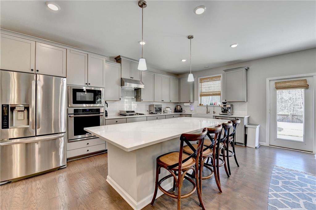 955 Laura Jean Court Buford, GA 30518 - Photo 29 of 68 a kitchen with stainless steel appliances granite countertop a table chairs refrigerator and microwave