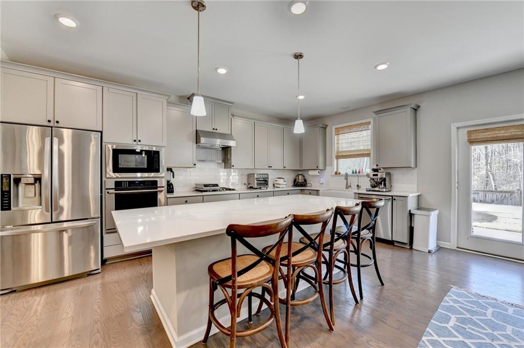 955 Laura Jean Court Buford, GA 30518 - Photo 30 of 68 a kitchen with stainless steel appliances granite countertop a refrigerator a stove a sink a dining table and chairs with wooden floor
