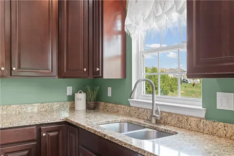 a kitchen with stainless steel appliances granite countertop a refrigerator a sink dishwasher a oven and a dining table with wooden floor
