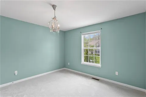 an empty room with windows and chandelier fan