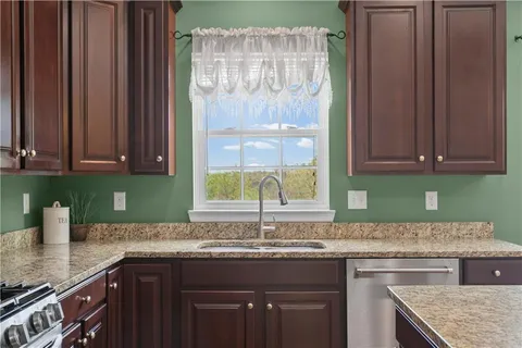a kitchen with stainless steel appliances granite countertop a refrigerator a sink dishwasher a stove and a refrigerator