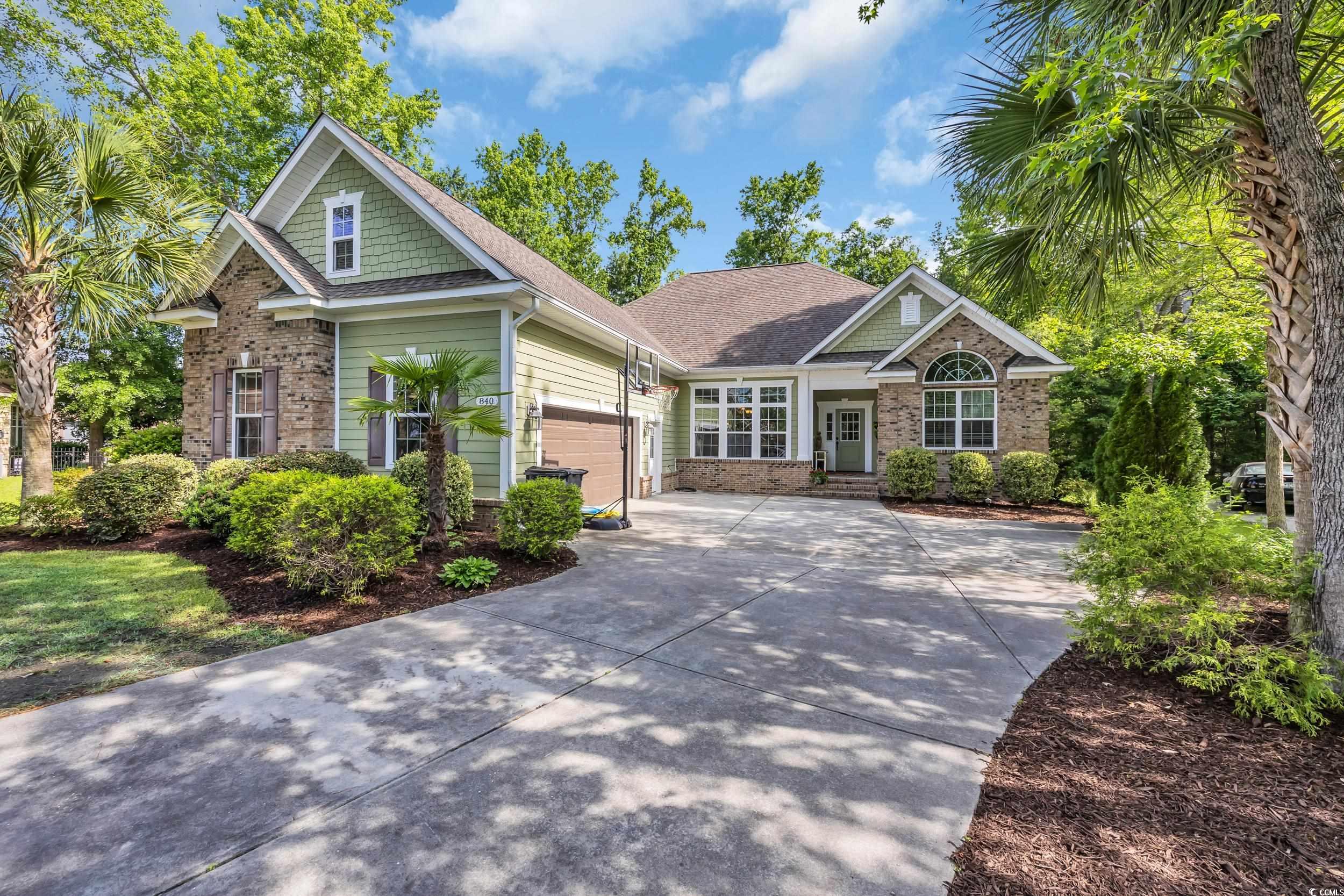 Craftsman-style home with concrete driveway, brick siding, an attached garage, and roof with shingles