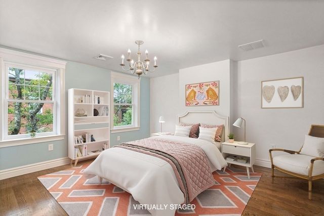 a spacious bedroom with a bed a chandelier and a window