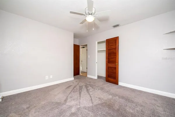an empty room with closet and a ceiling fan