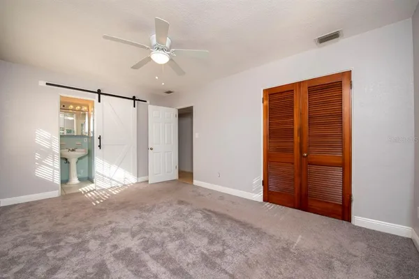 an empty room with closet and a ceiling fan