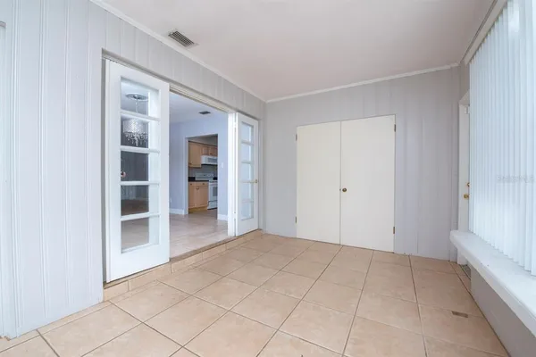 a view of an empty room with kitchen and window