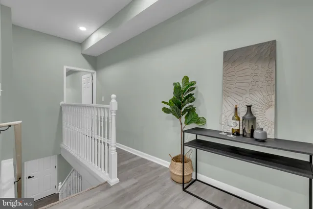 a view of a hallway to a livingroom with wooden floor and stairs