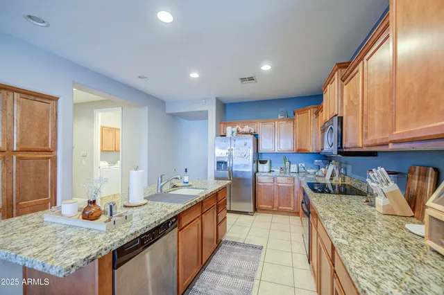 a kitchen with stainless steel appliances granite countertop sink stove refrigerator and cabinets